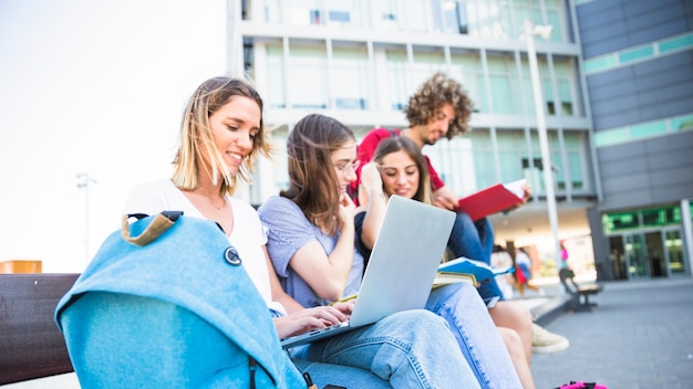 Female using laptop near studying friends