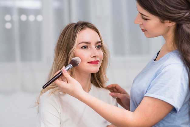 Free photo female visagiste doing makeup to blonde