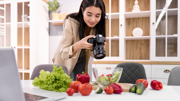 カメラで写真を撮る自宅で女性のvlogger