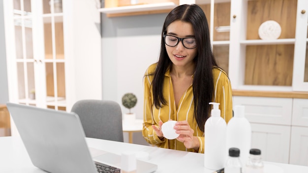 Female vlogger at home with laptop and bottles