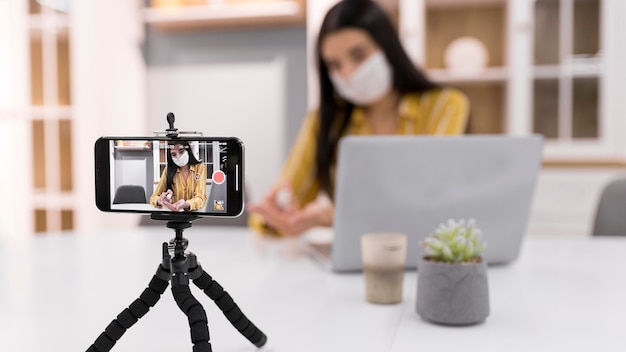 Foto gratuita vlogger femminile a casa con laptop e smartphone