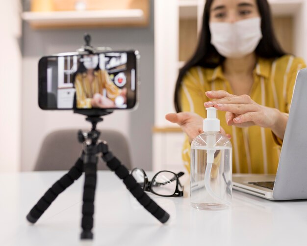 スマートフォンと手指消毒剤を使用して自宅で女性のvlogger