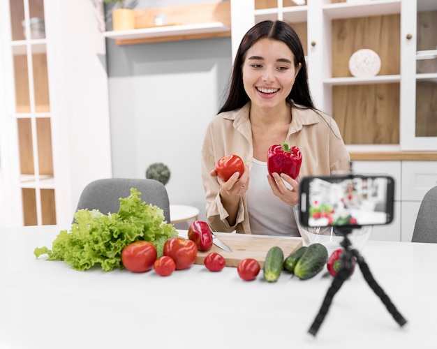 スマートフォンと野菜を持って自宅で女性のvlogger