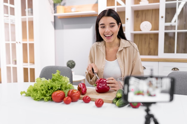 Vlogger femminile a casa con verdure e smartphone