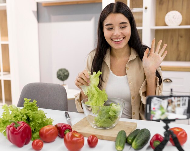 スマートフォンと野菜を使って自宅でvlogを作成する女性
