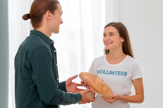 Free photo female volunteer giving out bread to person in need