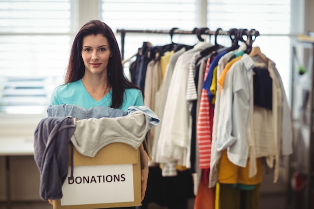 Female volunteer holding clothes in donation box