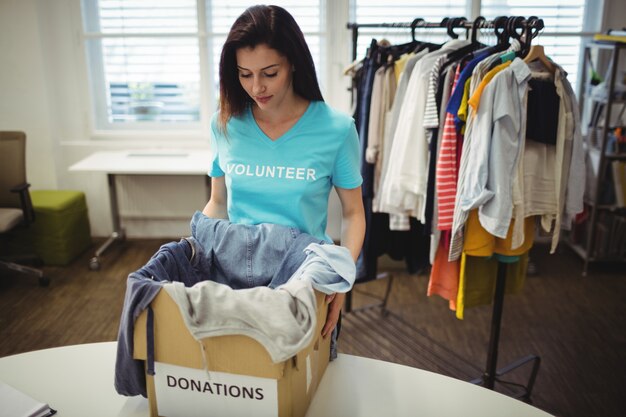 Female volunteer holding clothes in donation box