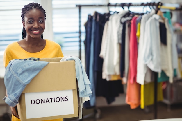 Женский добровольца держа одежду в ящик для пожертвований