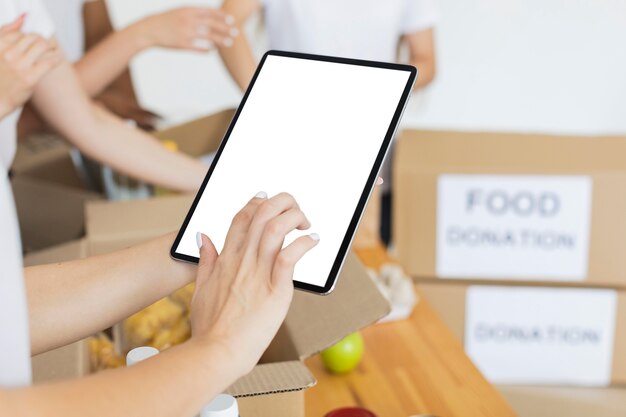 여성 자원 봉사자 태블릿을 사용하여 식품 기부 상자 준비