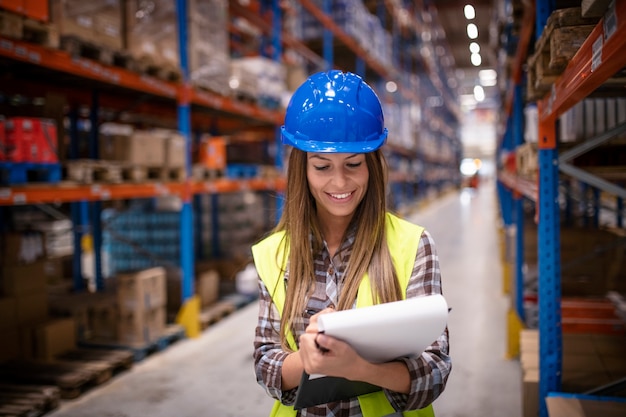 female warehouse worker checking supply in large distribution warehouse storage area