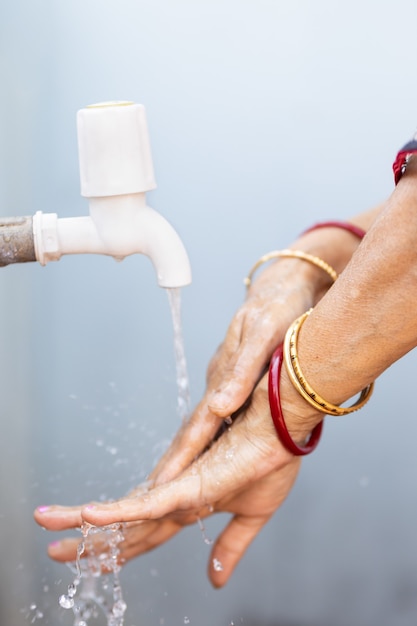 蛇口の下で手を洗う女性-COVID-19パンデミック中に手を洗うことの重要性