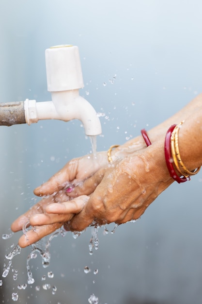 Free photo female washing hands under the faucet - importance of washing hands during the covid-19 pandemic