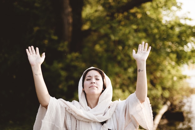 Free photo female wearing a biblical gown whit her hands up towards the sky