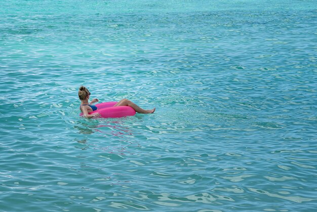 海のピンクのフロートでビキニを着ている女性