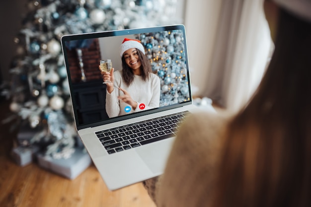 Female wearing santa hat while speaking with online friend on laptop