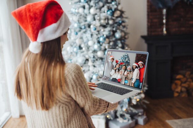 Female wearing santa hat while speaking with online friend on laptop