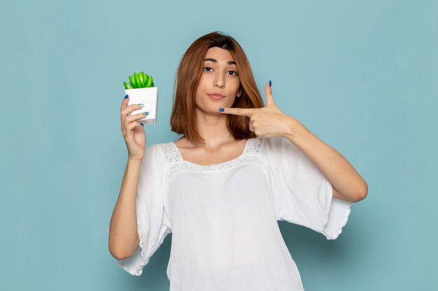 female in white blouse and blue jeans holding little plant