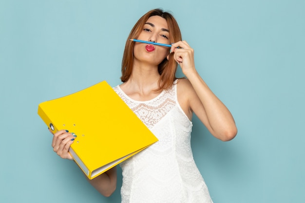 female in white blouse and blue jeans holding yellow files and pen