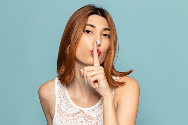 female in white dress posing showing silence sign