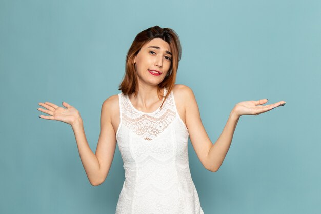 female in white dress posing with not knwoing expression