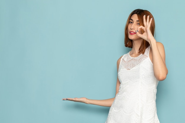 female in white dress showing alright sign