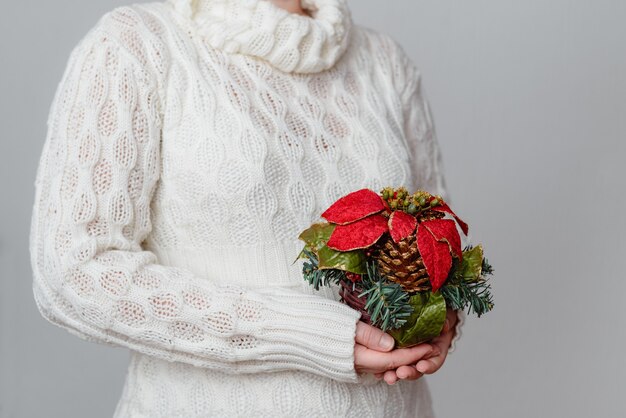クリスマス飾りを保持している白いセーターの女性