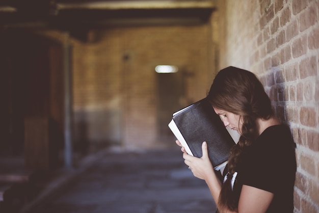 Donna con la bibbia contro la testa mentre prega