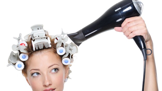 Female with black hairdryer drying female head in hair-curled - close-up