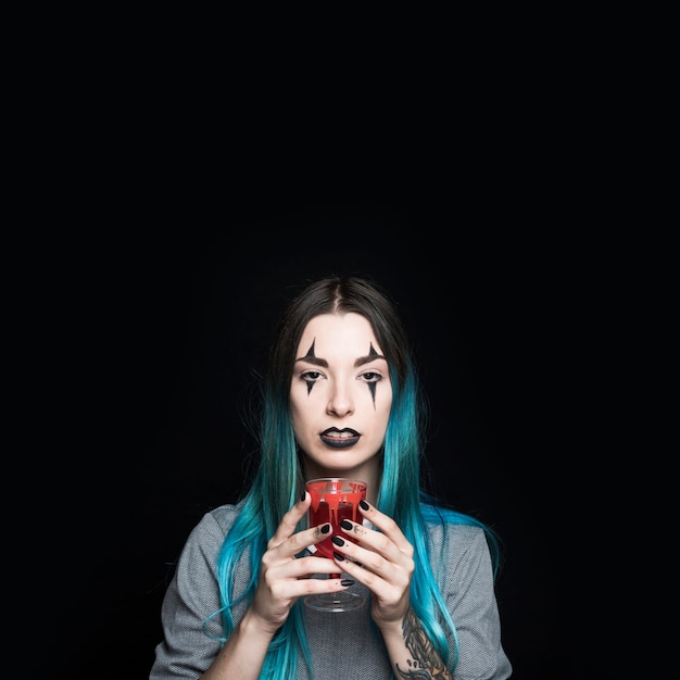 Female with creepy makeup holding bloody goblet