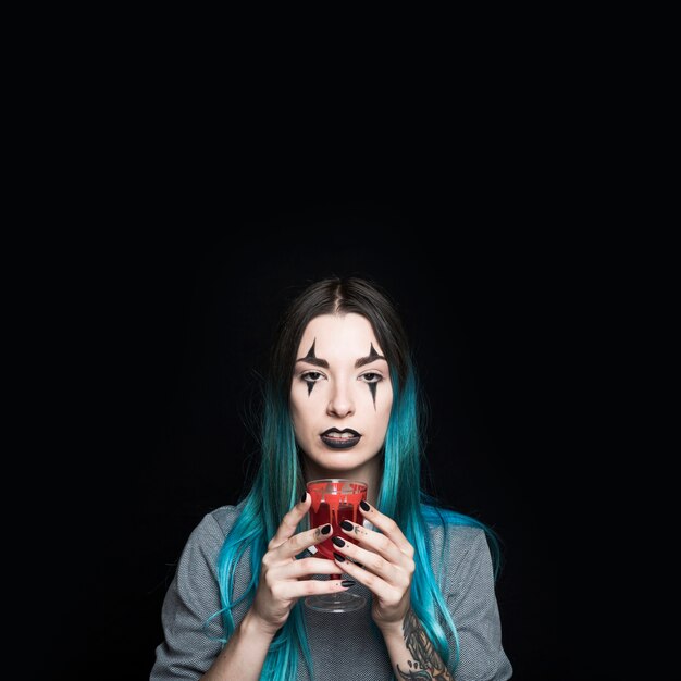 Female with creepy makeup holding bloody goblet