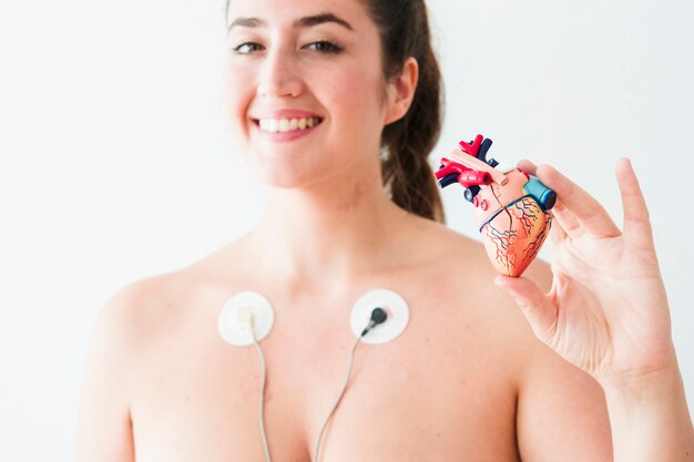 Female with electrodes holding figurine of heart