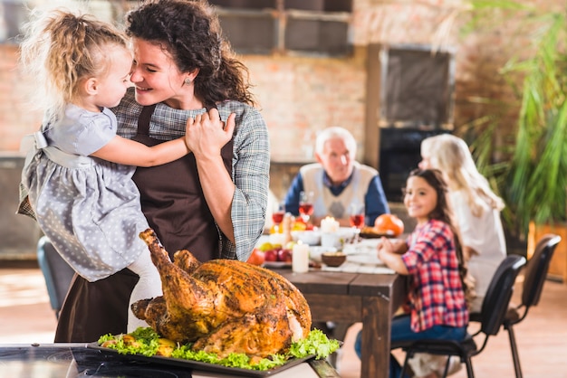 Female with girl in arms near roasted ham