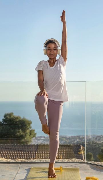 Foto gratuita femmina con le cuffie facendo fitness a casa