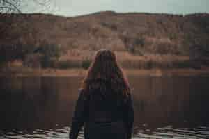 Free photo female with long hair looking at a beautiful lake in a forest