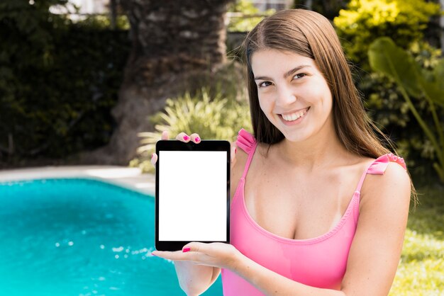 Female with tablet with clear display near pool