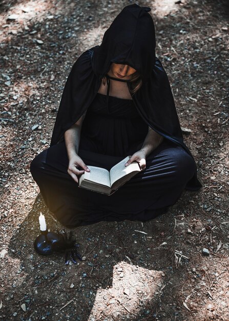 여성 마법사 열린 책과 숲 바닥에 앉아