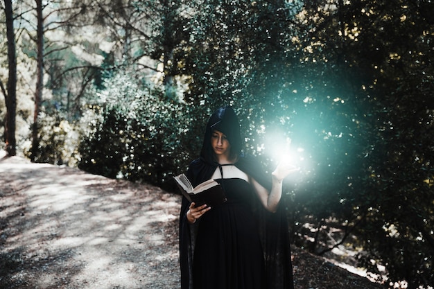 Бесплатное фото Женский волшебник, практикующий колдовство в солнечном лесу