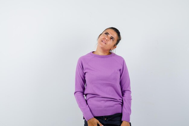 Female in wool blouse looking up and looking hesitant 