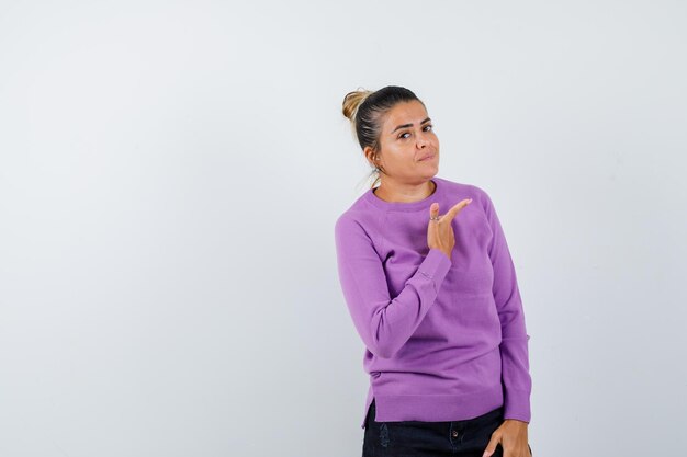 Female in wool blouse pointing away and looking confident 