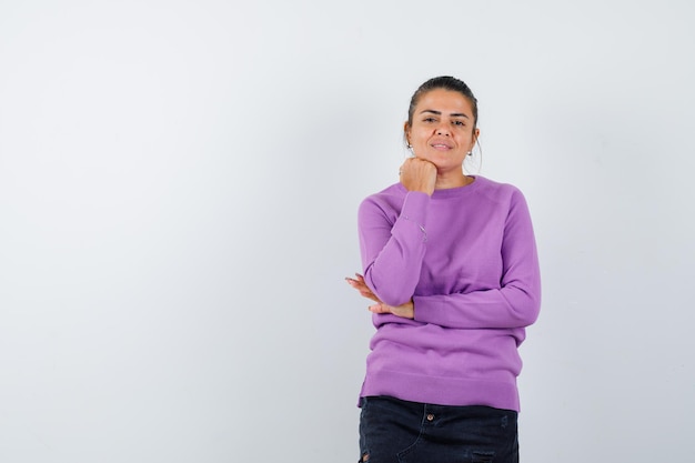 Female in wool blouse propping chin on hand and looking sensible 