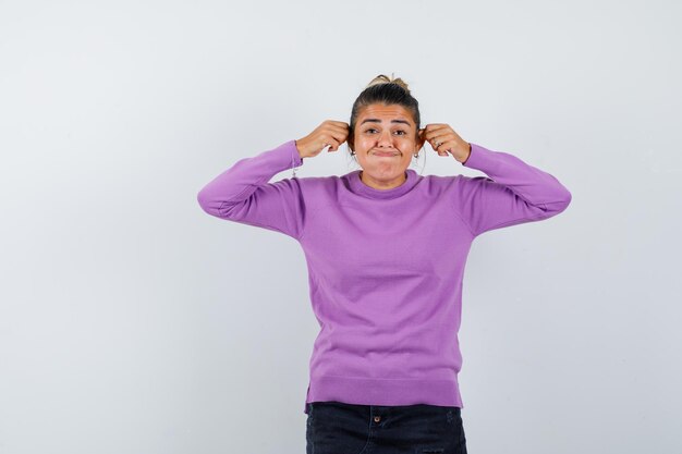 Female in wool blouse pulling down her ears and looking funny 