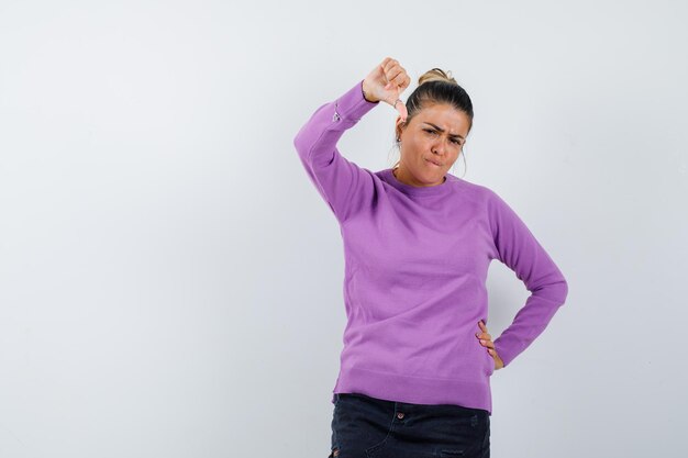 Female in wool blouse showing thumb down and looking disappointed 