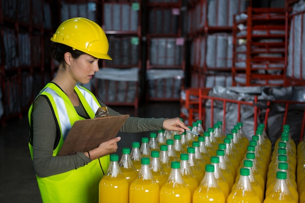 Free photo female worker examining juice bottles