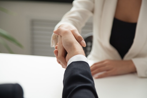 Female worker greeting business partner with handshake
