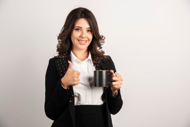 Female worker holding tea and giving thumbs up