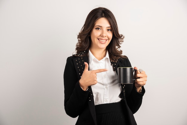 Female worker holding tea and pointing at it