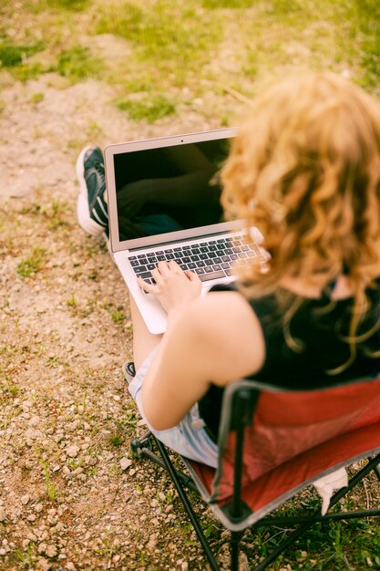 Femmina che lavora al computer portatile sul fondo della natura