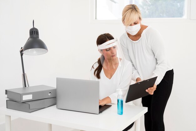 Женщина работает в офисе и носить защиту лица вид спереди