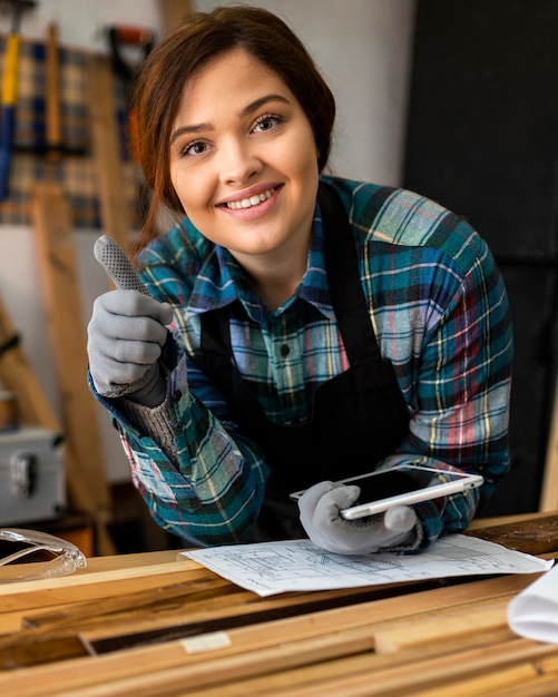 Female in workshop holding tablet and showing ok sign